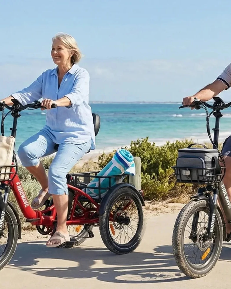 Two adults riding Ridewave electric tricycles on a coastal bike path, enjoying a stable and comfortable ride.