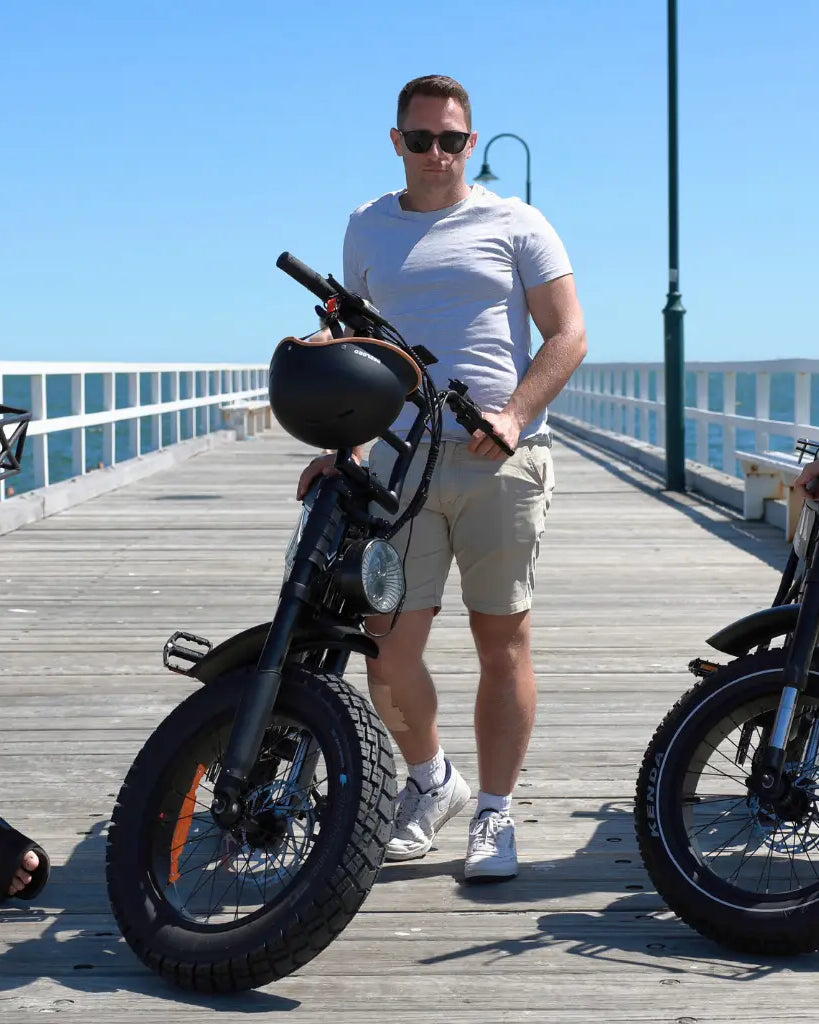 Three people standing in front of fat tyre electric bikes outdoors in Australia