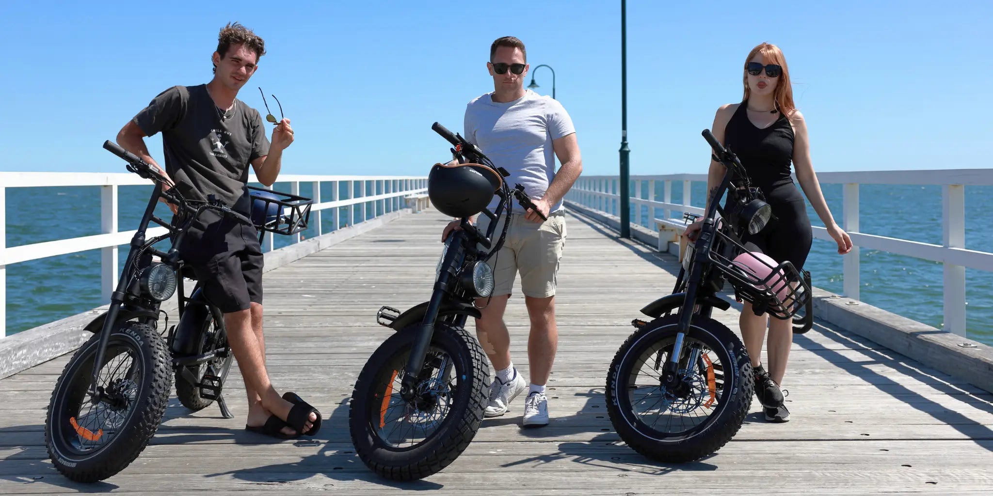 Three people standing in front of fat tyre electric bikes outdoors in Australia