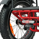 Close-up of a red bicycle frame with a black tire and orange rim on a white background